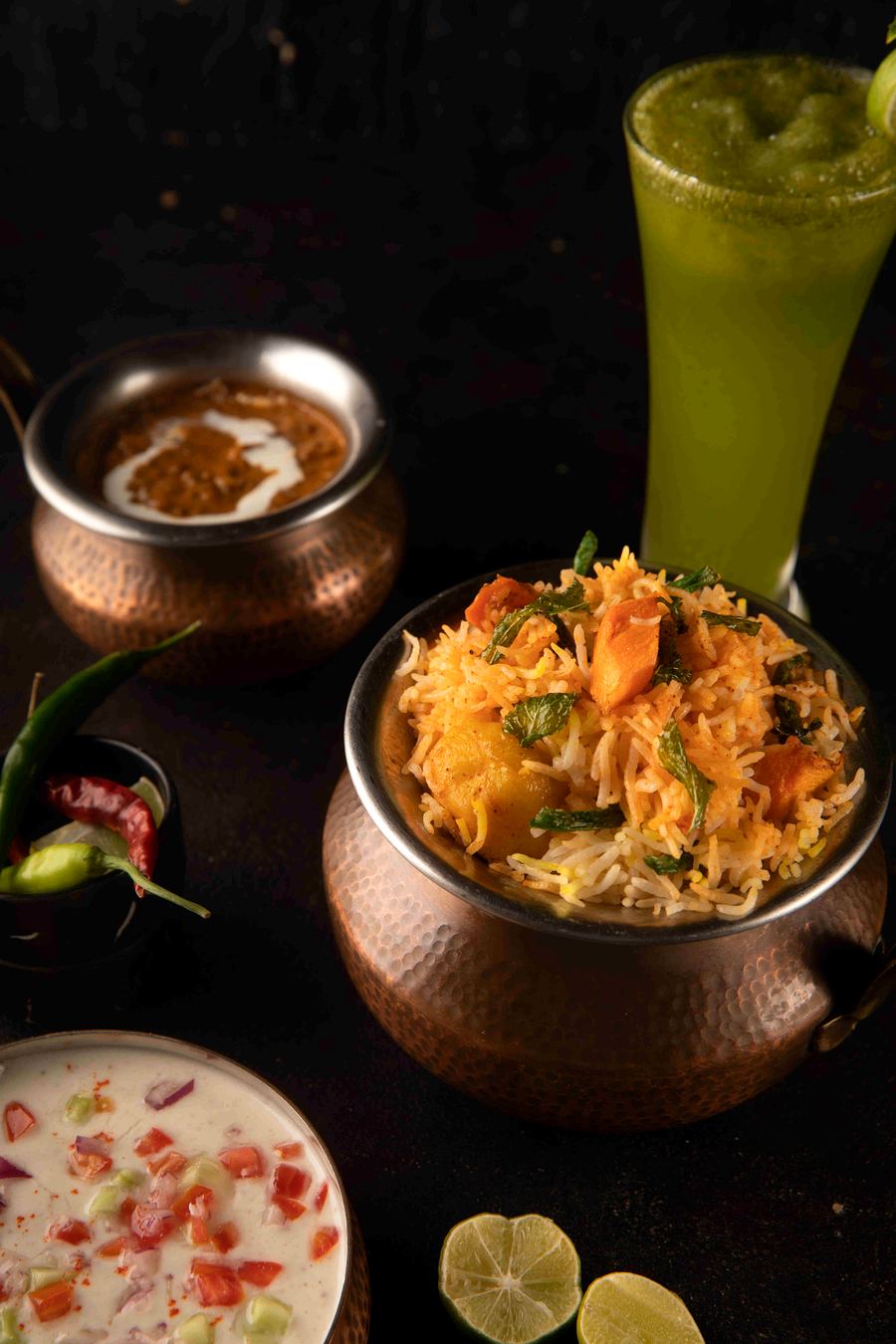 Subz dum biryani served in a copper handi with raita